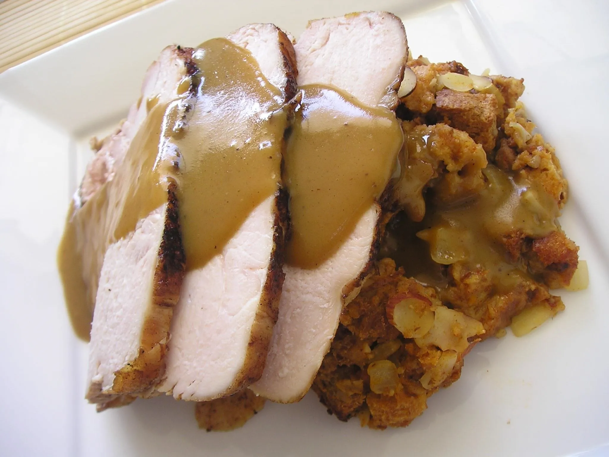 Sliced roasted turkey with gravy served over stuffing.