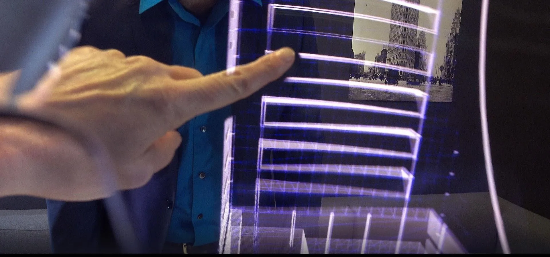 Hand pointing at a digital display with layered visuals.