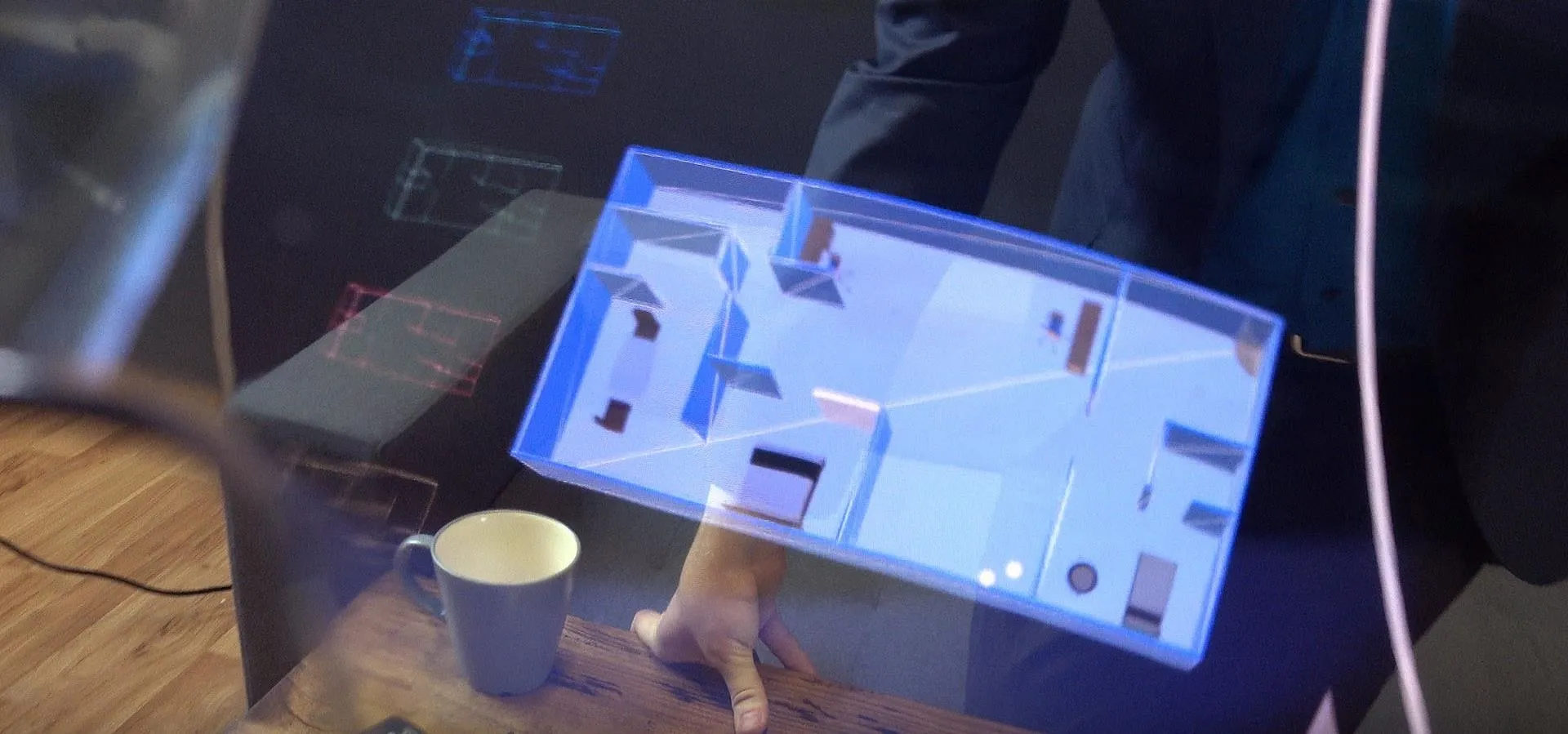 Interactive holographic display showcasing a floor plan with a coffee cup in the foreground.