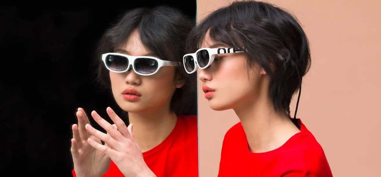 Model wearing stylish sunglasses and a red top.