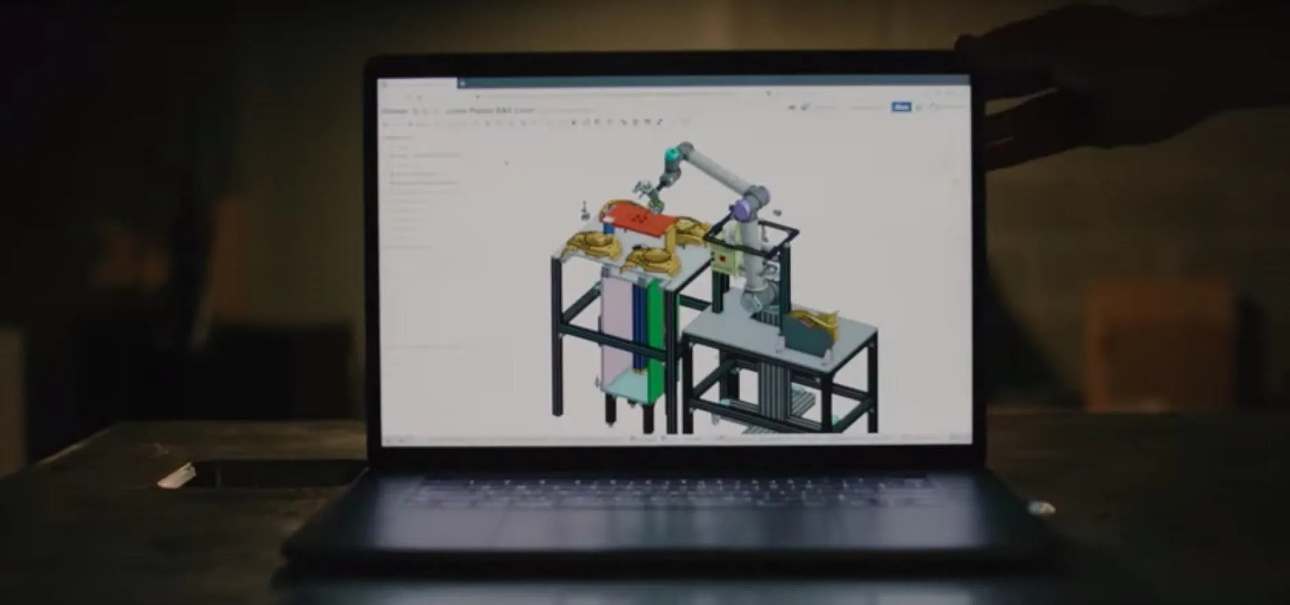 3D model of an automated assembly system displayed on a laptop screen.