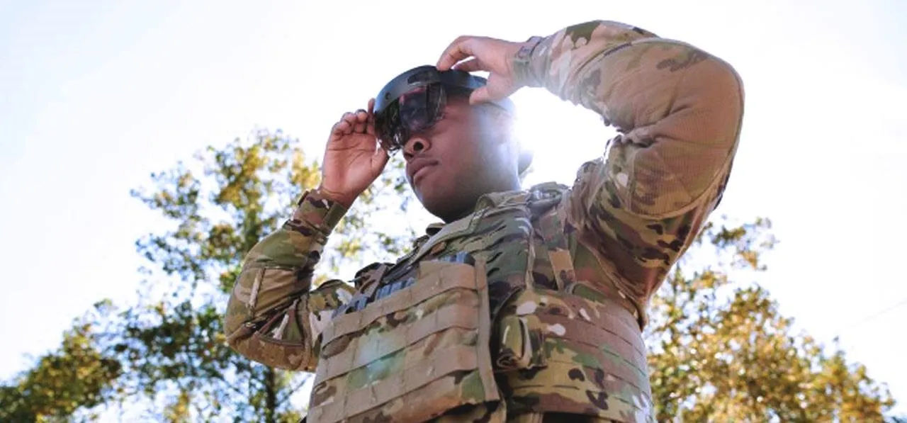 Soldier adjusting sunglasses outdoors.